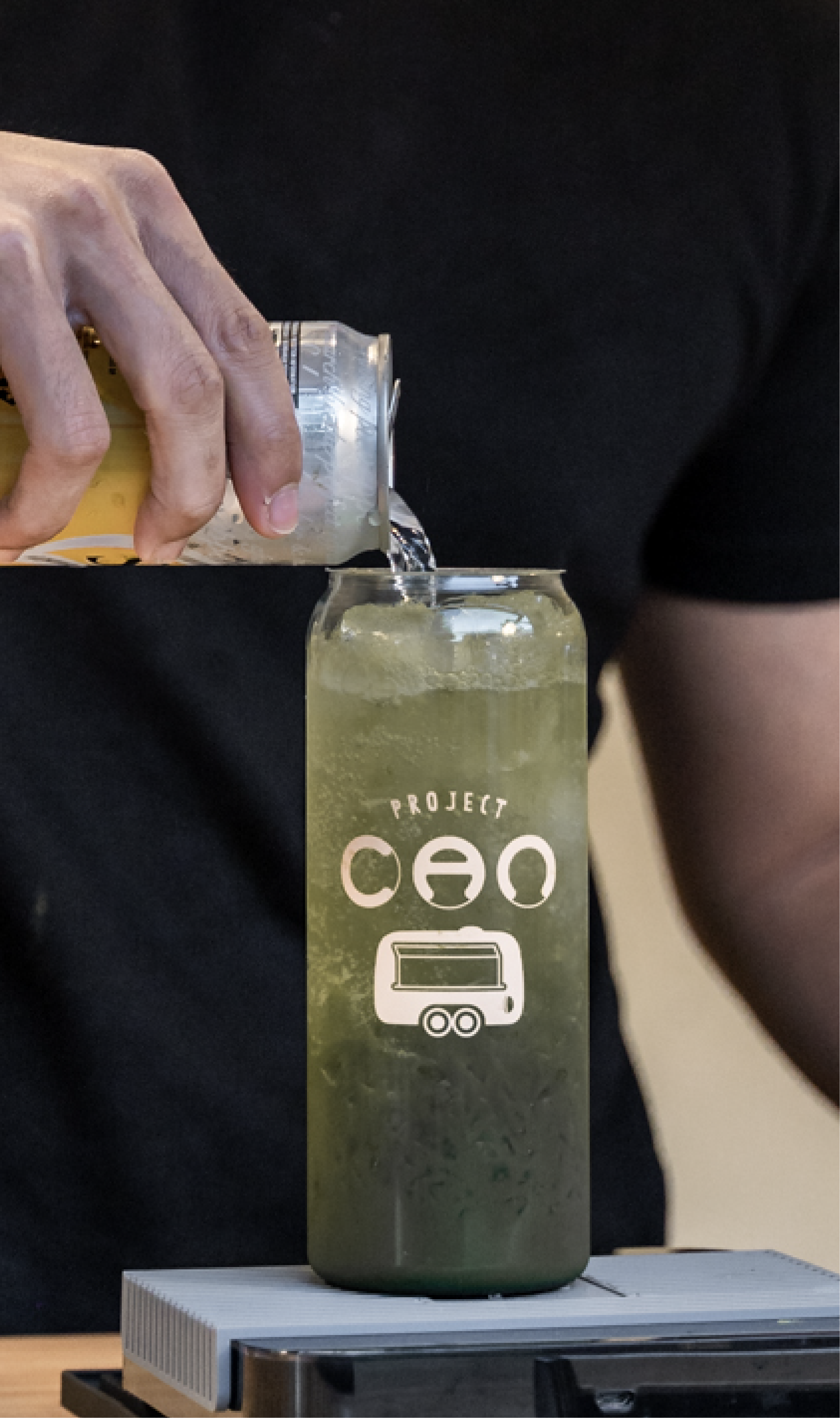 A branded Project CAN tall glass being poured with a green refresher.
